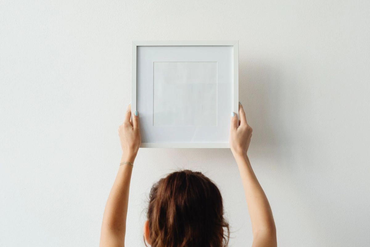 Ingelijst werk wordt aan een wand gehangen